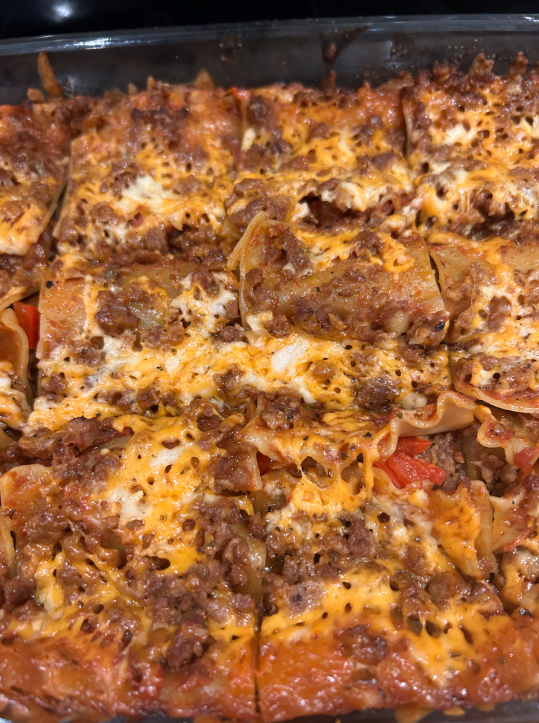 Picture of lasagna cut into square pieces. The top layer is visible with meat, cheese, and sauce.
